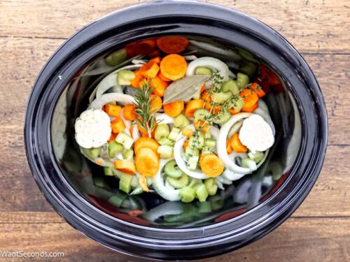 Step 1 how to make crockpot turkey breast, Prepare the turkey + crockpot. Arrange the veggies and herbs at the bottom of the crockpot.