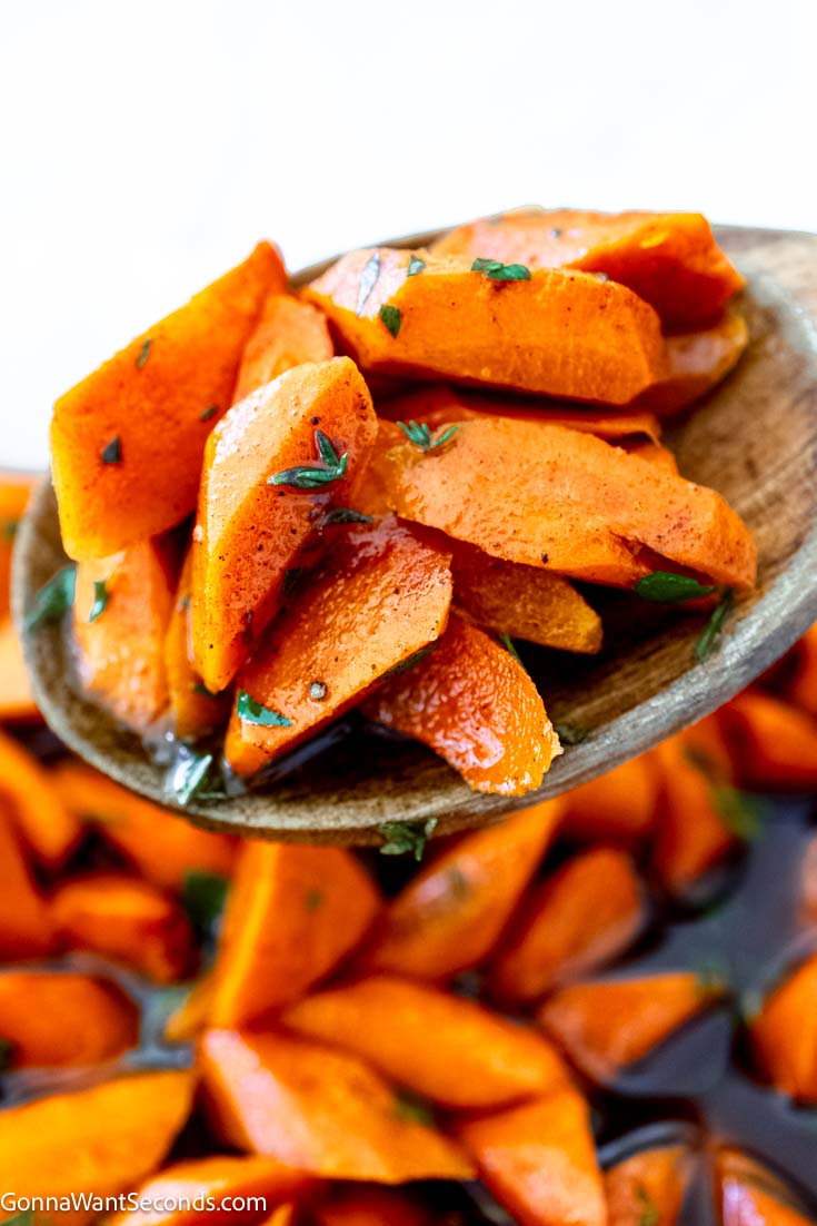 Soft, sweet, and buttery candied carrots with a rich brown sugar glaze. Easy oven recipe that’s perfect for holidays or weeknights. #candiedcarrots #carrots wooden spoon scooped roasted candied carrots