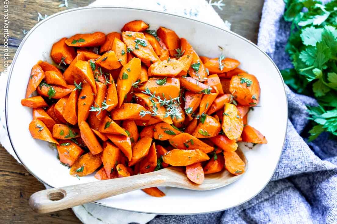candied roasted carrots in a serving platter with wooden spoon