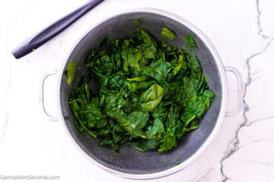 Step 2 how to make creamed spinach with cream cheese, Boil the spinach for a minute. Transfer it to a colander and drain well. Roughly chop it.
