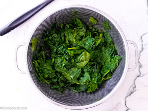 Step 2 how to make creamed spinach with cream cheese, Boil the spinach for a minute. Transfer it to a colander and drain well. Roughly chop it.