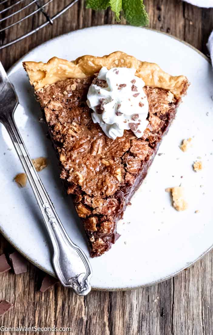 Rich and smooth, my fudge pie is simple to make and will knock your socks off! We deepen the chocolate filling with a little espresso powder and add pecans. #fudgepie #chocolatepie a slice of chocolate fudge pie topped with whipped cream