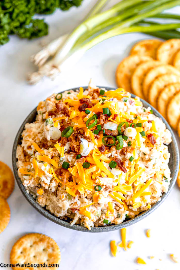 Million dollar dip is thick, creamy, and flavorful. Made with 4 different kinds of cheese, bacon bits, and almonds. Serve it with chips or veggies! #milliondollardip #diprecipes million dollar dip with bacon in a bowl