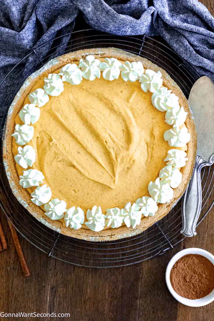 This no bake pumpkin pie takes 15 minutes or less to make and tastes fabulous. No oven, no mess! Using a pre-make graham cracker crust, it's so easy to make. #nobakepie #pumpkinpie whole no-bake pumpkin pie top shot