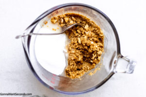 Step 1 how to make pumpkin cheesecake, Make the crust: Combine gingersnap crumbs, melted butter, and sugar.