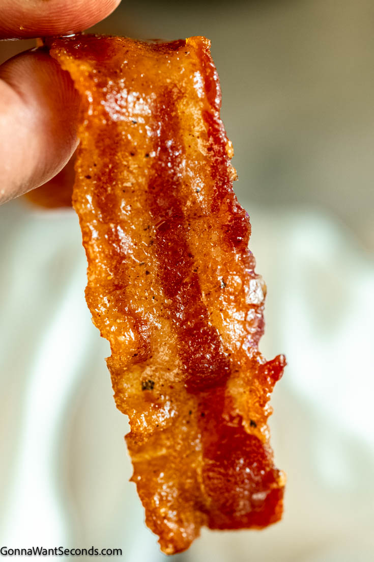 Million dollar bacon is a sweet and spicy strip of crispy heaven, with its candy coating on smoky bacon, making it an irresistible, finger-licking treat. #bacon #milliondollarbacon Close up of a strip of Million dollar bacon