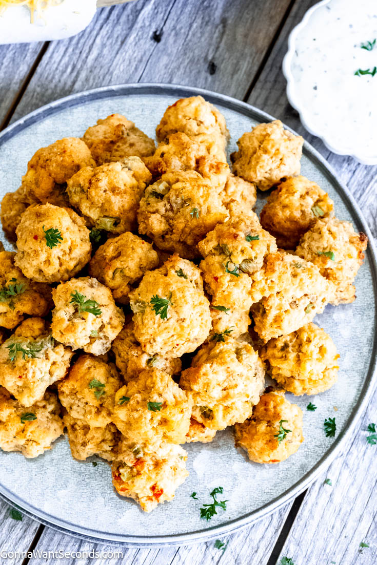 These moist and savory pimento cheese sausage balls are one of my favorites because these little appetizers are crispy on the outside and moist on the inside. #sausageballs #pimentocheese a pile of Pimento Cheese Sausage Balls on a plate