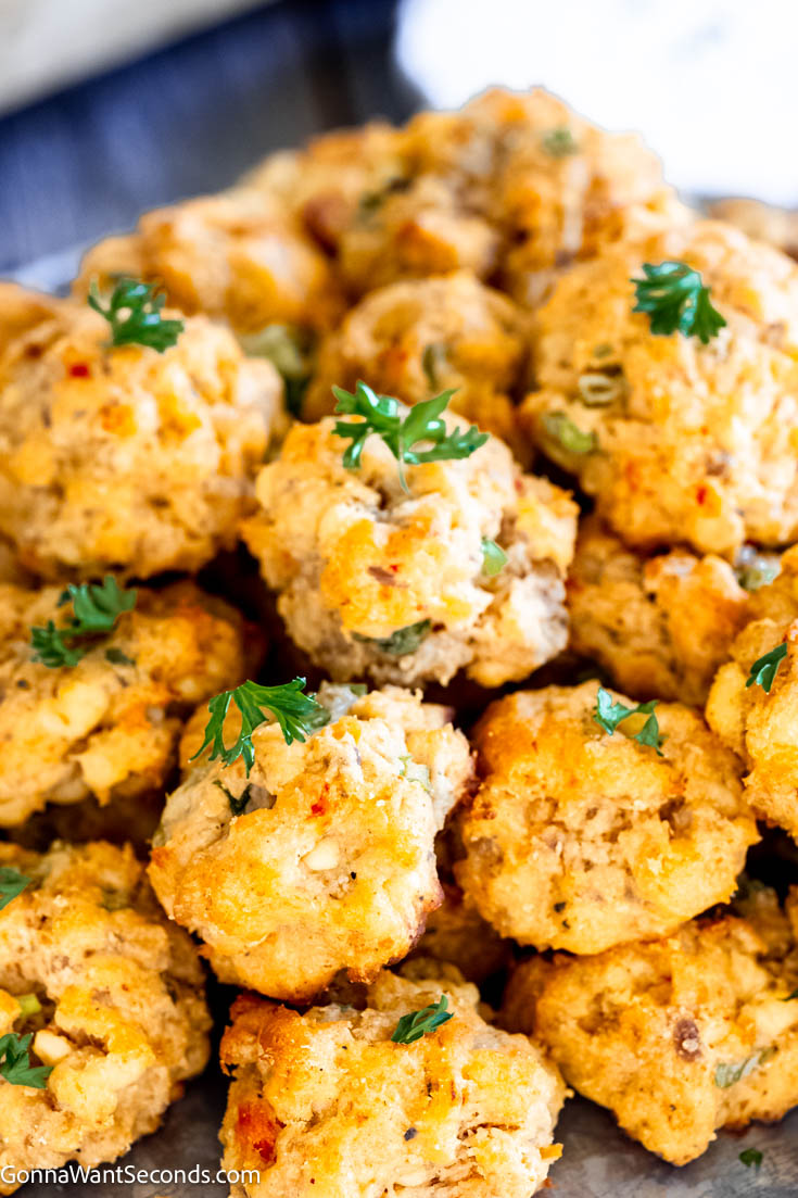 These moist and savory pimento cheese sausage balls are one of my favorites because these little appetizers are crispy on the outside and moist on the inside. #sausageballs #pimentocheese a pile of Pimento Cheese Sausage Balls close up