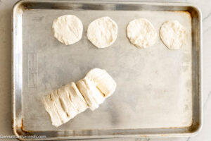 Step 2 how to make Pull Apart Garlic Bread, Remove biscuits from tube and separate into individual biscuits. Split each biscuit in half. You will have 16 halves.