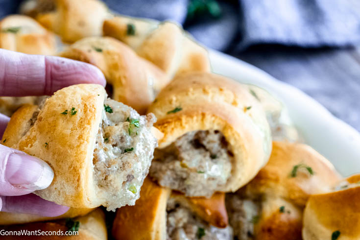 hand holding a piece of sausage cream cheese crescents