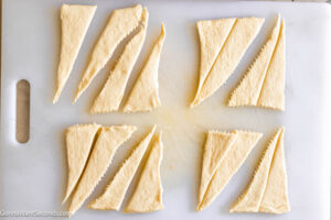 Step 5 how to make Sausage Cream Cheese Crescents, Cut each one in half vertically from the tip.
