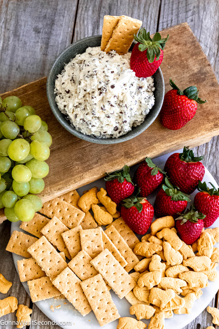 Booty dip is a sweet and creamy no-bake dip. This delicious dessert dip is made with cream cheese, marshmallow fluff, Cool Whip, and mini chocolate chips. #dessertdip #bootydip Booty dip in a bowl with crackers and fruits