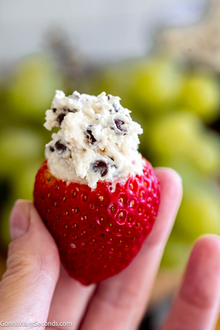 Booty dip is a sweet and creamy no-bake dip. This delicious dessert dip is made with cream cheese, marshmallow fluff, Cool Whip, and mini chocolate chips. #dessertdip #bootydip Booty dip dessert on top of a fresh strawberry