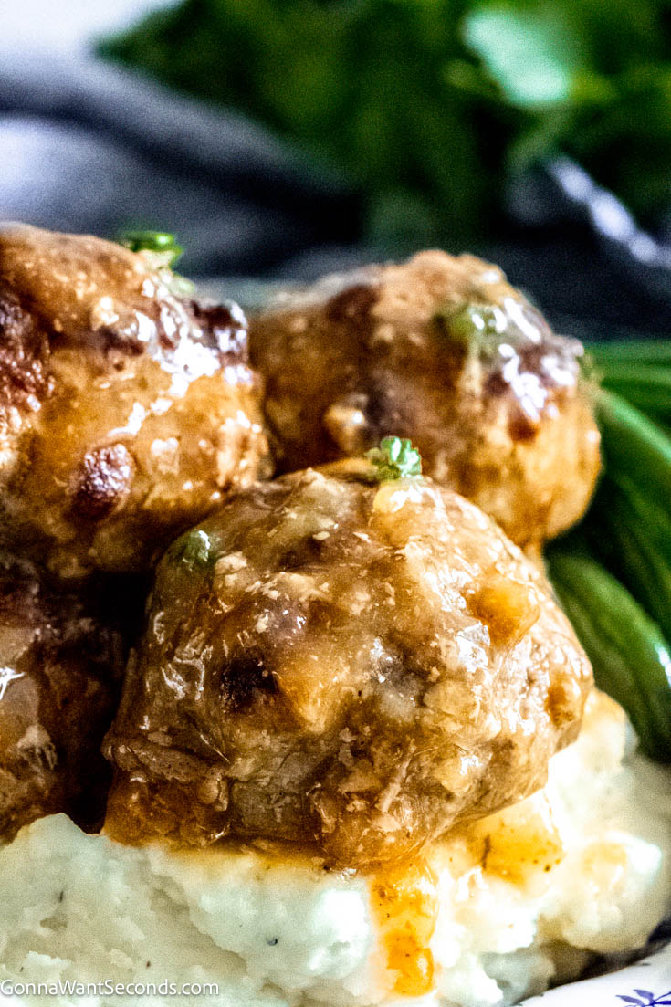Our Crockpot Mississippi meatballs follow the delicious Mississippi recipes tradition. Moist tender meatballs in a brothy gravy flavored with pepperoncini, ranch dressing and au jus gravy. #crockpotmeatballs #mississippimeatballs Mississippi meatballs with beef broth on top of mashed potatoes with green beans on the side
