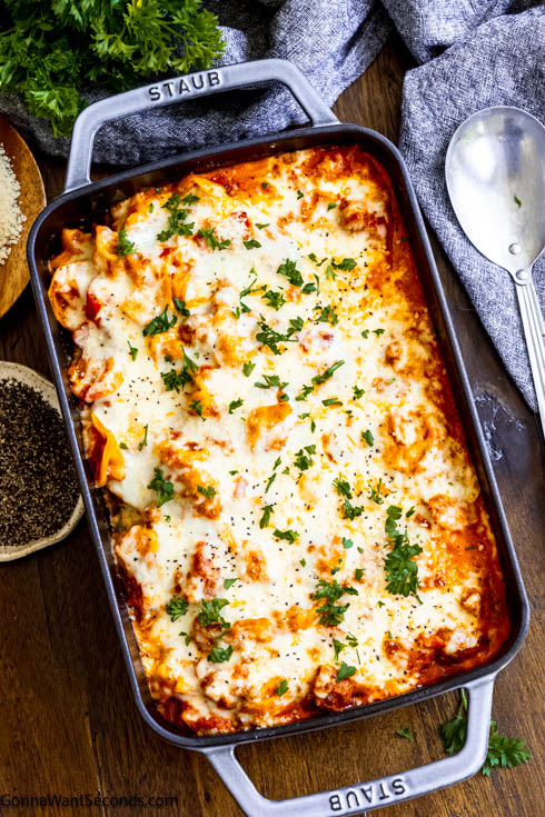 This quick and heart-warming Tortellini casserole is loaded with onions, bell peppers, Italian sausage, and tortellini in creamy tomato sauce. #tortellinicasserole #pastacasserole tortellini casserole topped with melted cheese