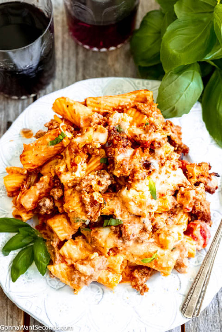 Baked rigatoni is a cheesy casserole with layers of meaty sauce, with ricotta cheese filling, topped with mozzarella cheese, parmesan, and rigatoni pasta. #rigatoni #bakedrigatoni baked rigatoni with sausage on a plate