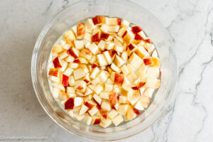 Step 6 how to make Creamy Fruit Salad, Fill a bowl of water and add lemon juice and mix. Add apples and let it sit for 10 minutes. Drain.