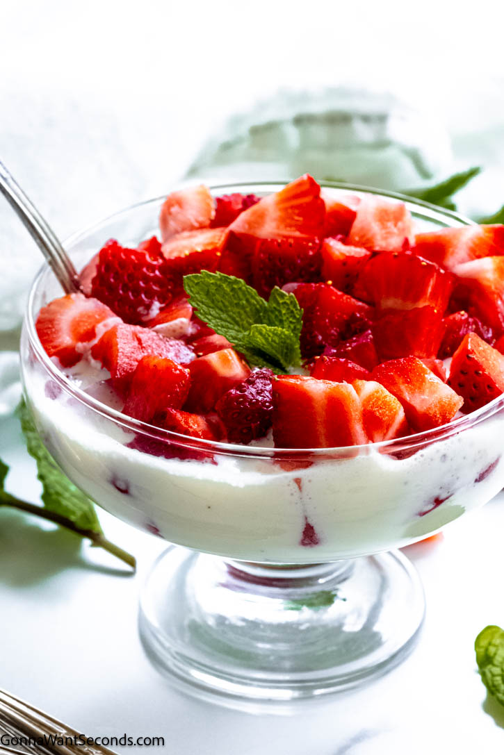 This frescas con crema just may become your new favorite breakfast, snack, or dessert. Sweet, juicy strawberries are bathed in a rich, sweet, and very mildly tangy sauce! #strawberries #frescasconcrema frescas con crema in a dessert bowl