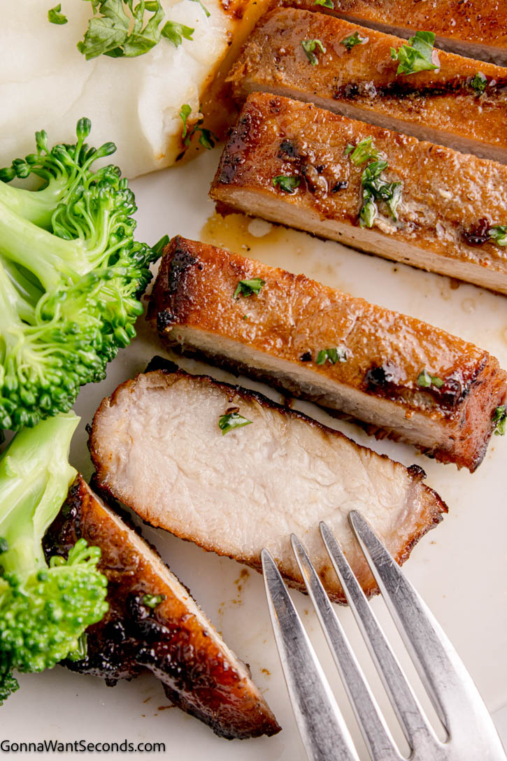 My grilled boneless pork chops is so moist and juicy. Using our quick and easy 60-minute recipe and a good grilling technique, you'll have perfect sear and tender results every time. #porkchops #grilledporkchops slice of grilled boneless pork chops on a plate