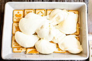 Step 5 how to make no bake lemon icebox cake, Scoop half the pudding mix over the layer of Chessman cookies.