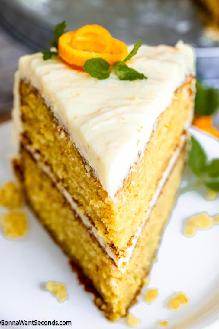 This light and fluffy orange cake has a tender, moist crumb and is packed with natural orange flavor. It is soaked in orange syrup and with orange zest-scented cream cheese frosting. #orangecake #layeredcake a slice of orange layer cake