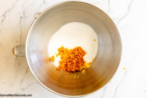 Step 1 how to make orange cake, In the bowl of a stand-up mixer, add sugar and orange zest.