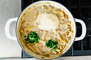 Step 9 how to make Rigatoni D, Add parmesan, basil, parsley, and cooked mushrooms. Simmer until the sauce thickens a bit.