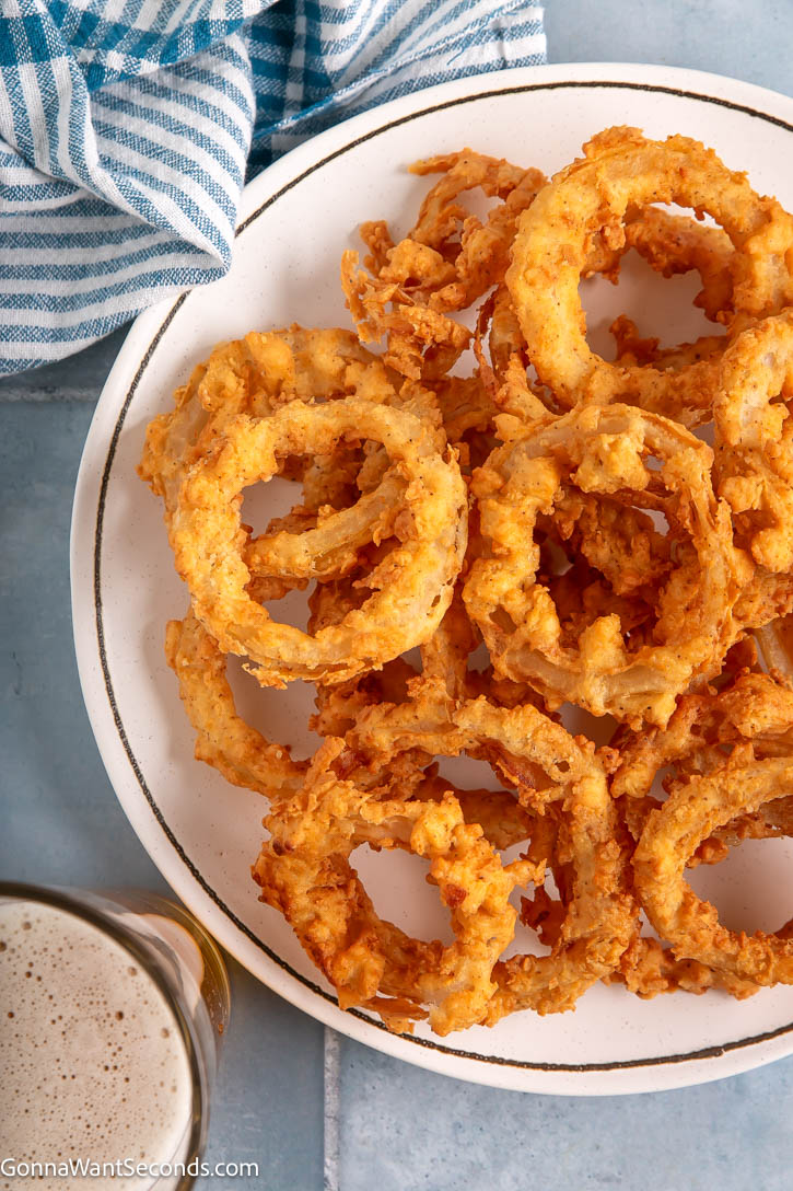Crispy, golden homemade onion rings! Double-dipped in seasoned flour for the ultimate crunch! Easy, crave-worthy, and perfect for dipping. #onionrings #snacks Onion Rings on a plate