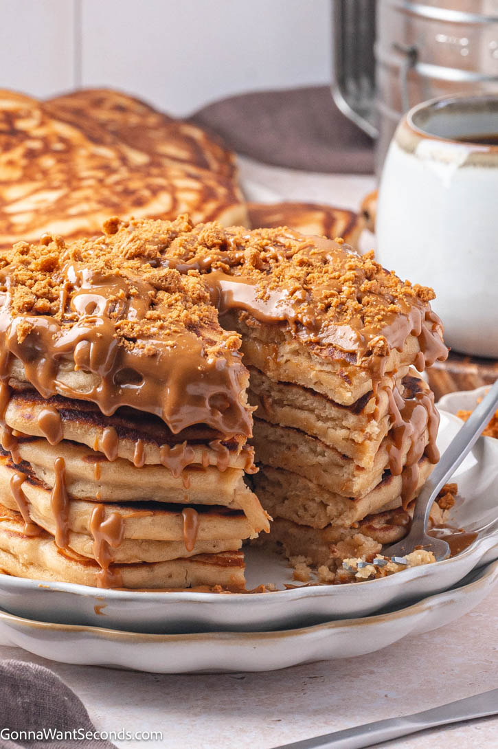 Fluffy, golden Biscoff Pancakes with cookie butter, whipped cream, and cookies — the perfect cozy breakfast treat. #pancakes #biscoffpancakes A stack of Biscoff Pancakes with cookie butter on top, dripping with warmed cookie butter