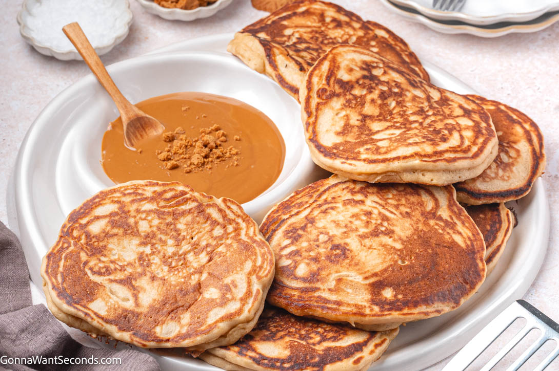 Fluffy, golden Biscoff Pancakes with cookie butter, whipped cream, and cookies — the perfect cozy breakfast treat. #pancakes #biscoffpancakes Biscoff Pancakes with warmed cookie butter on the side