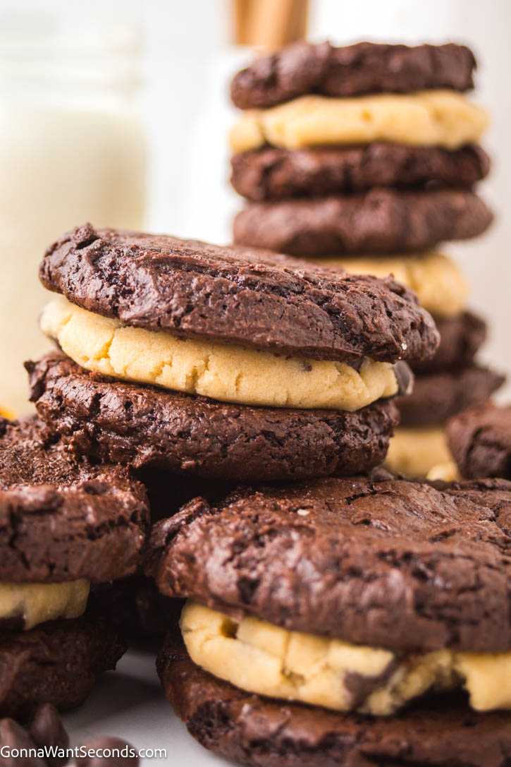 Indulge in brownie cookies with cookie dough filling. This fun dessert is rich, fudgy, and utterly irresistible for all ages. #browniecookies #cookiedough a pile of Brownie Cookies with Cookie Dough Filling