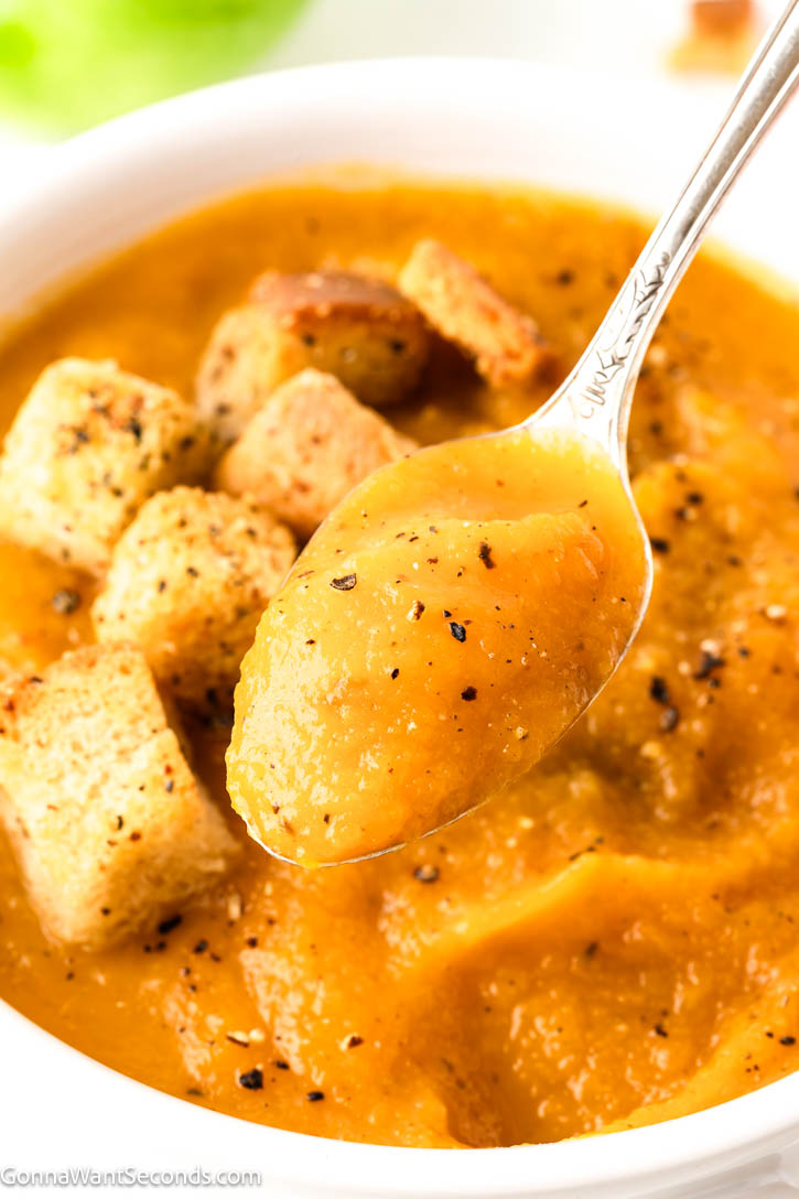Cozy butternut squash and apple soup with roasted veggies, lemon, and cream. Velvety, balanced, and perfect for chilly nights or holidays. #butternutsquashsoup #applesoup spoon scooping Butternut Squash And Apple Soup from a bowl