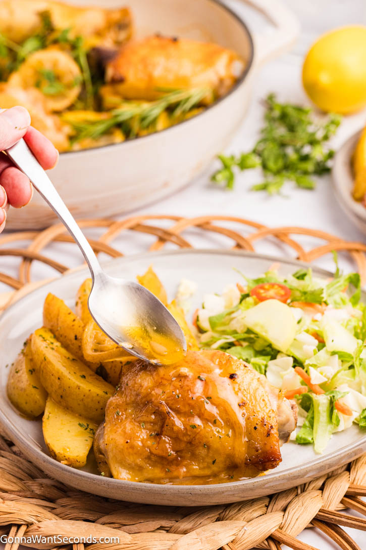 This Greek Lemon Chicken and Potatoes is a one-pan wonder—juicy chicken, tender potatoes, and bright lemon make an easy, cozy family dinner. #greekchicken #chickenandpotatoes spoon drizzling sauce over Greek Lemon Chicken with Potatoes