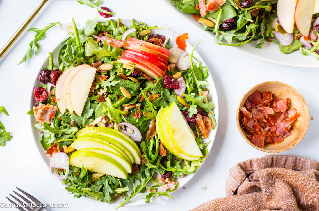 Crisp apples, goat cheese, cranberries, and prosciutto tossed in maple vinaigrette make this Harvest Salad the ultimate fall side dish. #fallsalad #harvestsalad fall harvest salad topped with sliced apples
