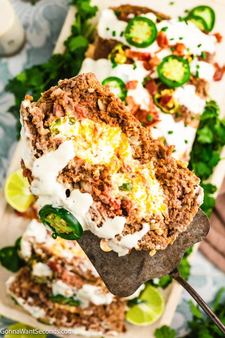 Spicy, cheesy Jalapeño Popper Meatloaf stuffed with cream cheese, cheddar, bacon, and jalapeños—comfort food made easy for family dinners. #jalapenopopper #meatloaf serving a slice of Jalapeño Popper Meatloaf with cheese filling
