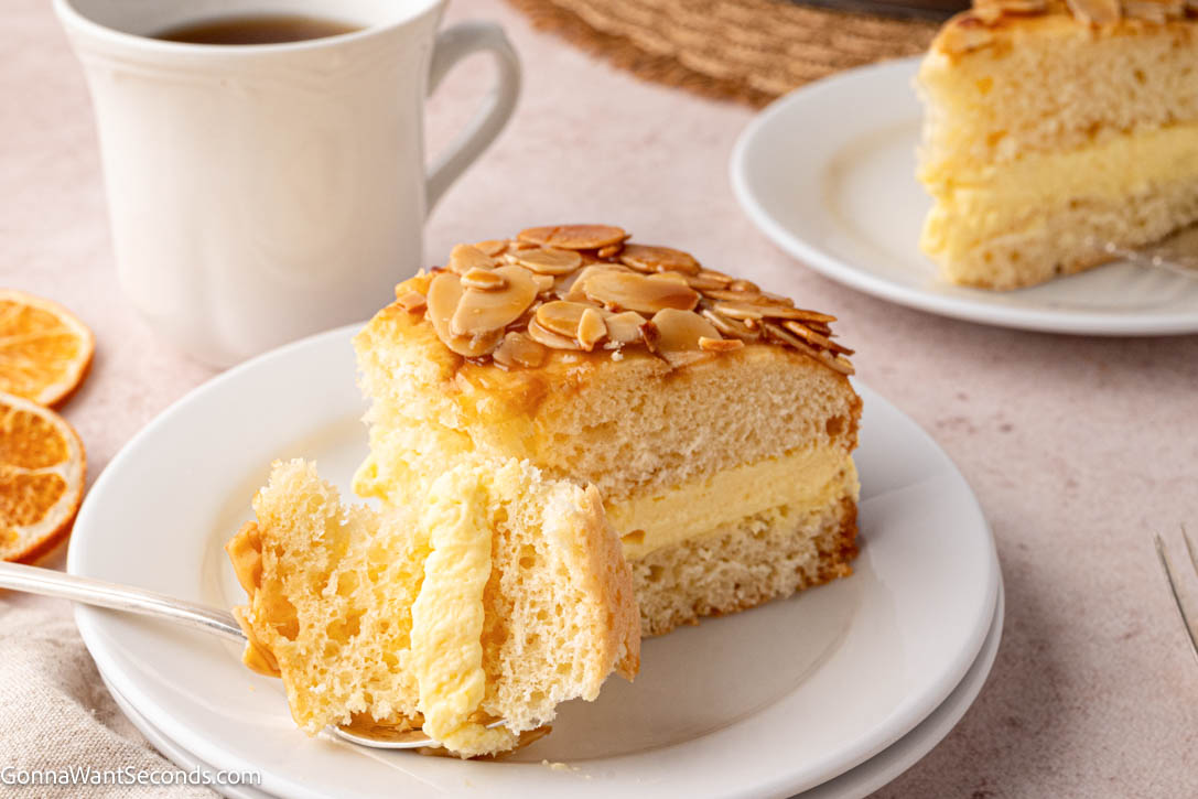 Bee Sting Cake features a soft brioche base, honey-almond topping, and creamy vanilla filling — a dreamy German dessert everyone will love! #beestingcake #bienenstich A slice of Bee Sting Cake with honey-almond topping and creamy vanilla filling