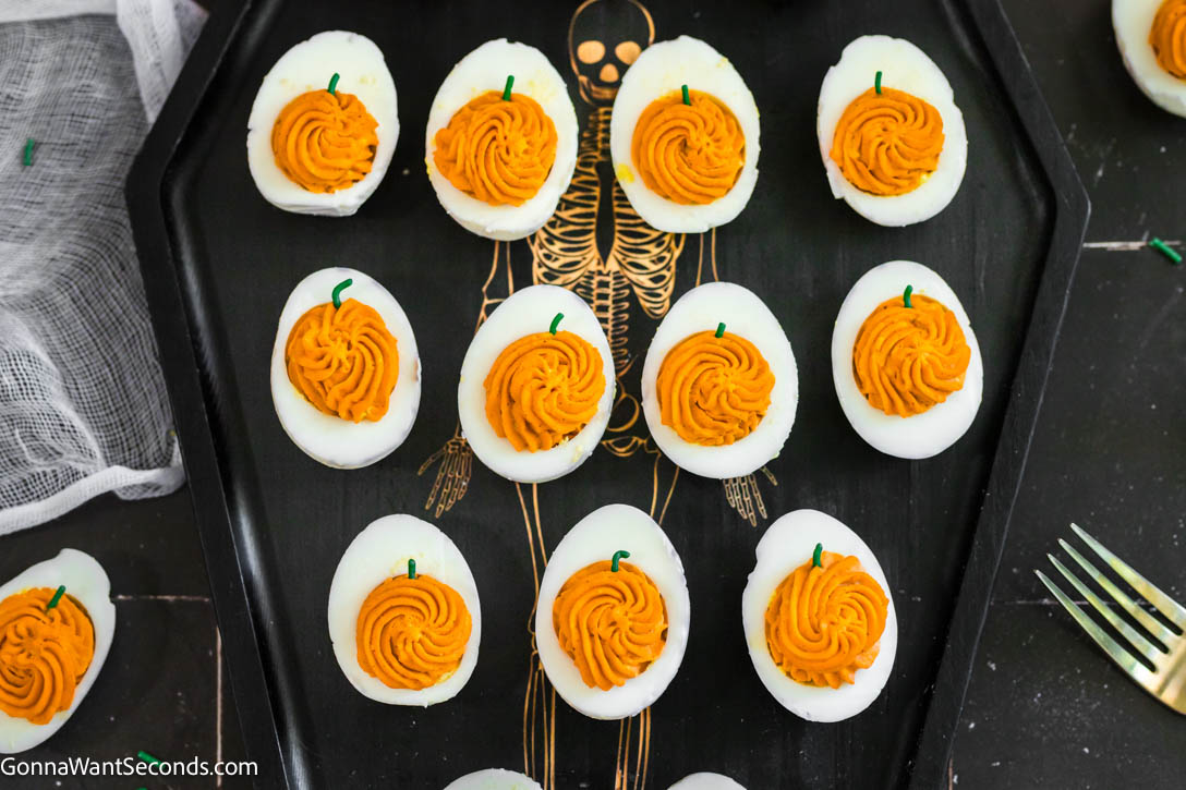 These spooky-cute Halloween Deviled Eggs have black-cracked shells and creamy orange filling. It's a stunning addition to any Halloween spread! #halloweenappetizers #deviledeggs Halloween Deviled Eggs on a serving tray