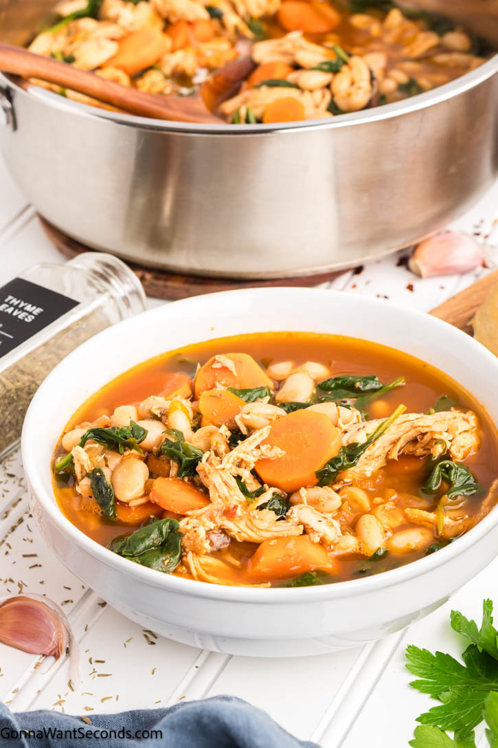 This Tuscan White Bean Soup is everything we crave in a cozy bowl — tender chicken, cannellini beans, carrots, and greens in a rich, herb-scented broth. #tuscansoup #whitebeansoup Tuscan White Bean Soup in a bowl