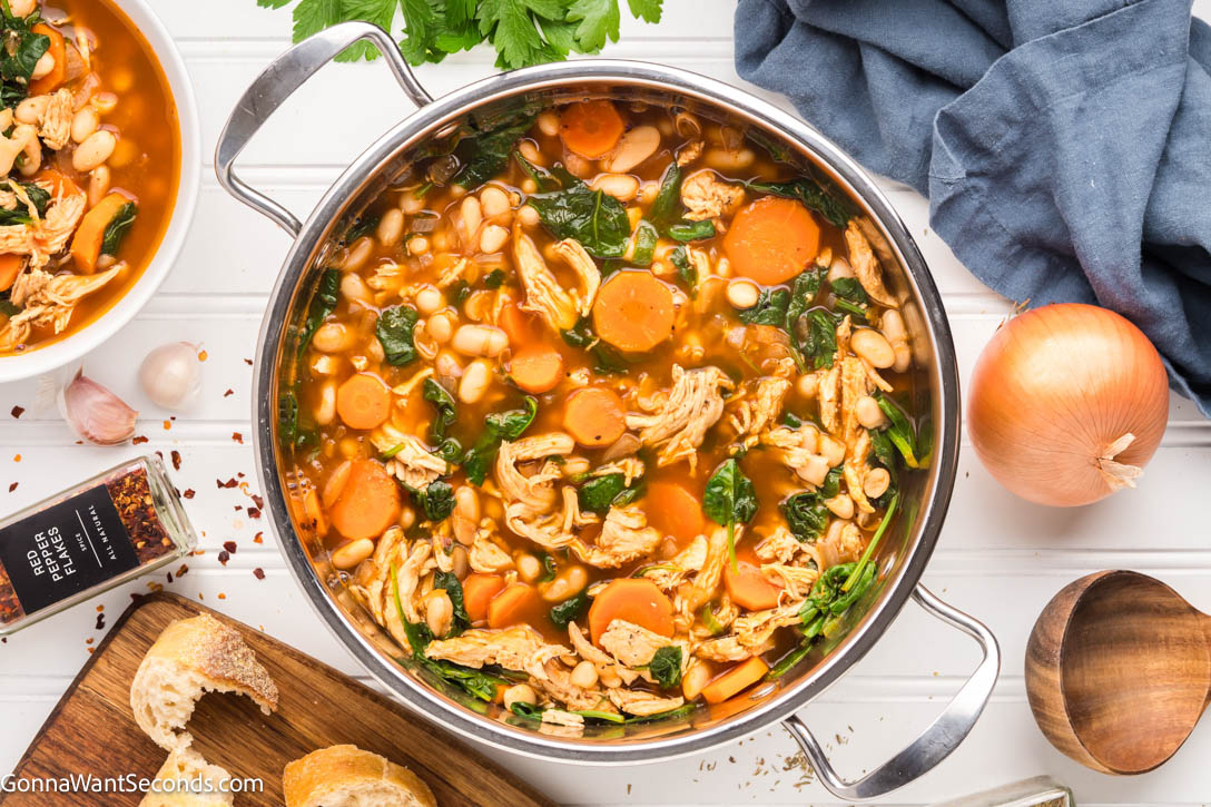 This Tuscan White Bean Soup is everything we crave in a cozy bowl — tender chicken, cannellini beans, carrots, and greens in a rich, herb-scented broth. #tuscansoup #whitebeansoup Tuscan White Bean Soup in a pot