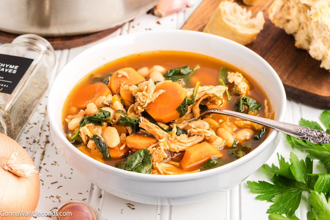 This Tuscan White Bean Soup is everything we crave in a cozy bowl — tender chicken, cannellini beans, carrots, and greens in a rich, herb-scented broth. #tuscansoup #whitebeansoup Tuscan White Bean Soup in a bowl