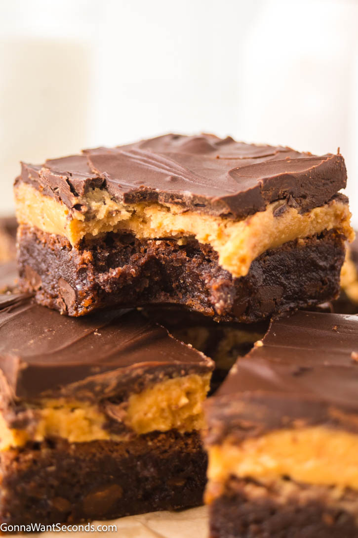 Ultra-fudgy Buckeye Brownies with a creamy peanut butter layer + glossy chocolate topping. A Nostalgic chocolate-PB dessert everyone loves. #buckeyerecipes #brownies Slices of Buckeye Brownies with a creamy peanut butter layer and glossy chocolate topping