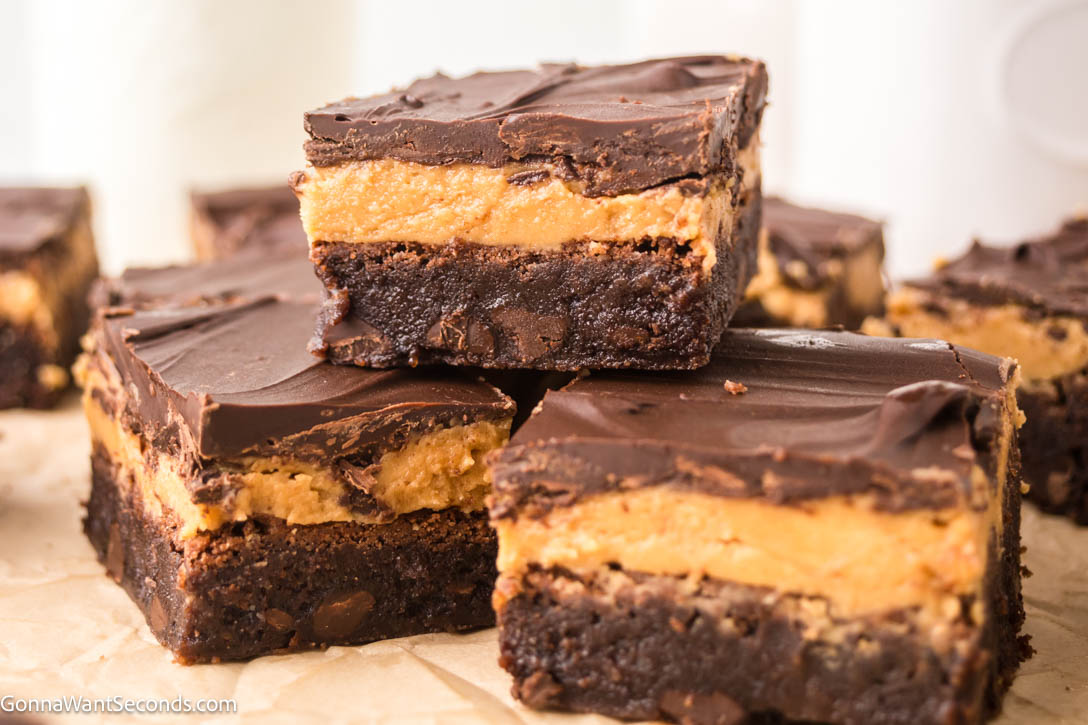 Ultra-fudgy Buckeye Brownies with a creamy peanut butter layer + glossy chocolate topping. A Nostalgic chocolate-PB dessert everyone loves. #buckeyerecipes #brownies Slices of Buckeye Brownies with a creamy peanut butter layer and glossy chocolate topping