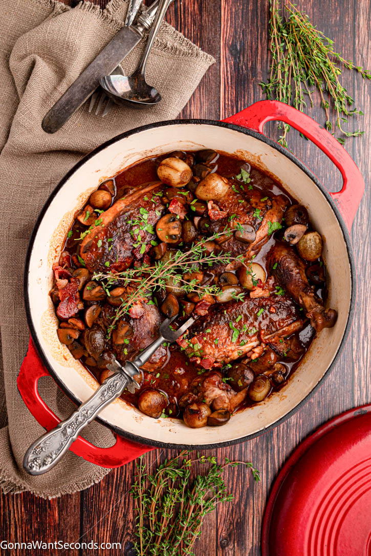 This cozy Coq Au Vin is tender chicken braised in red wine with bacon, mushrooms, and pearl onions—rich, rustic, and perfect for guests. #coqauvin #frenchchickenrecipes coq au vin with burgundy-colored sauce in a pot