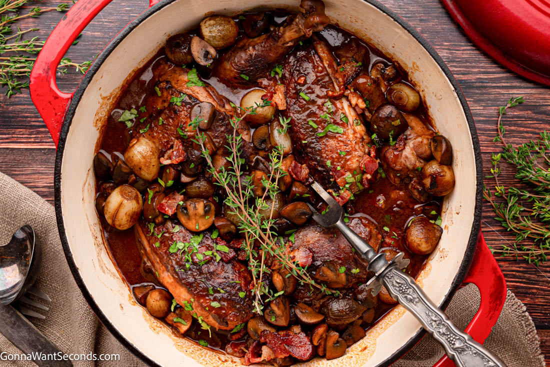 This cozy Coq Au Vin is tender chicken braised in red wine with bacon, mushrooms, and pearl onions—rich, rustic, and perfect for guests. #coqauvin #frenchchickenrecipes coq au vin with burgundy-colored sauce in a pot