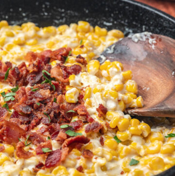 creamed corn with bacon on top, on a cast iron skillet