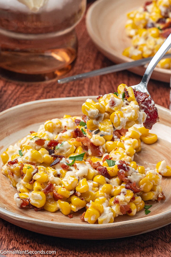 Rich, creamy, and smoky! This easy creamed corn with bacon and cream cheese is the ultimate cozy side dish for holidays or weeknight dinners. #creamedcorn creamed corn with bacon on top, on a plate