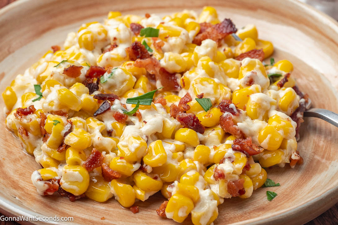 Rich, creamy, and smoky! This easy creamed corn with bacon and cream cheese is the ultimate cozy side dish for holidays or weeknight dinners. #creamedcorn creamed corn with bacon on top, on a plate