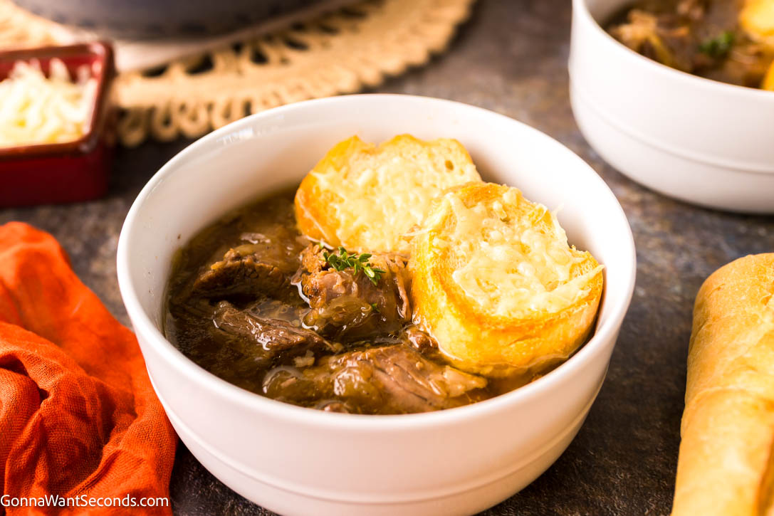 Tender beef, caramelized onions, and bubbly Gruyère make this French Onion Pot Roast a rich, comforting twist on the classic favorite. #frenchonion #potroast French Onion Pot Roast topped with baguette with melted cheese on top