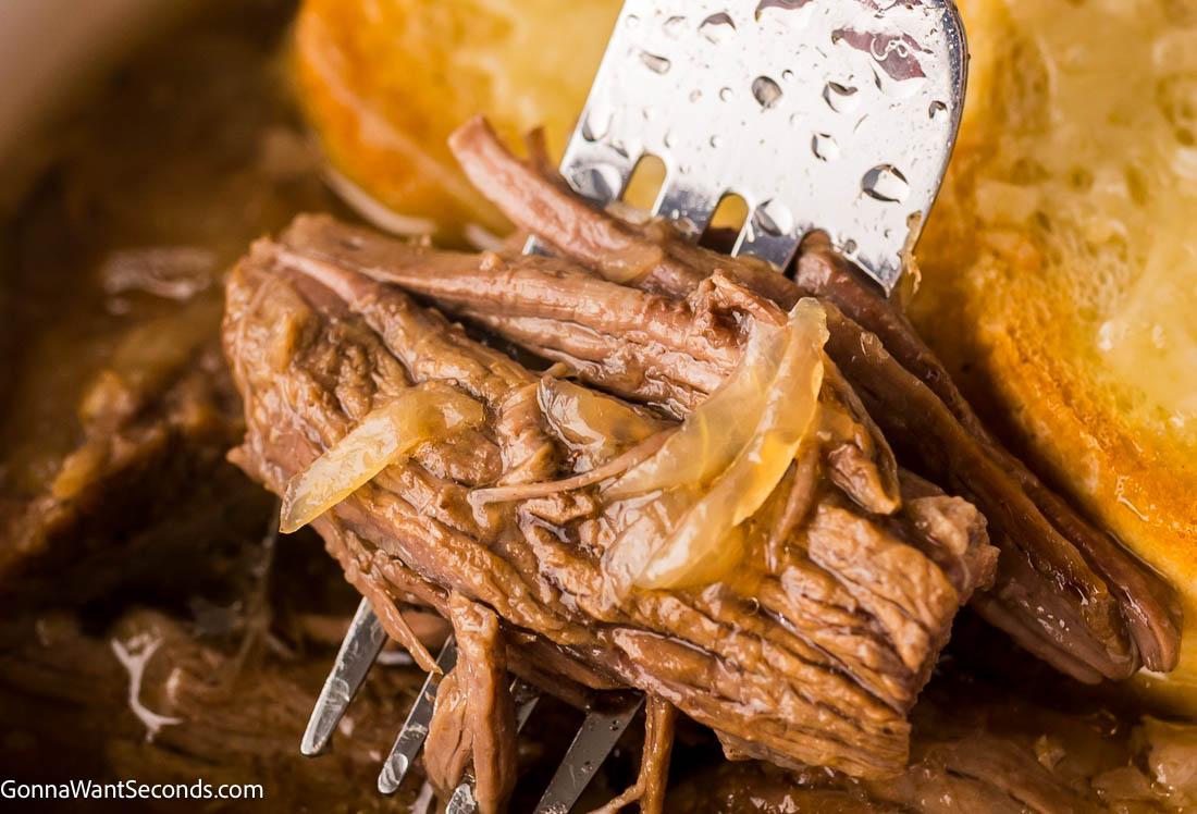 Tender beef, caramelized onions, and bubbly Gruyère make this French Onion Pot Roast a rich, comforting twist on the classic favorite. #frenchonion #potroast fork piercing a piece of French onion pot roast