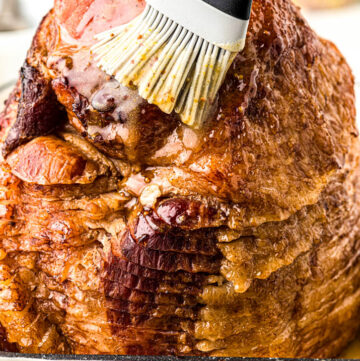 Brushing ham glaze all over the ham